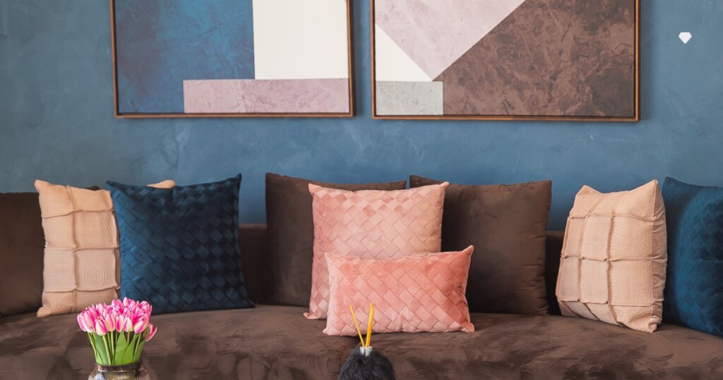 sala com sofá, almofadas coloridas e quadros na parede pintada de azul, uma das cores de cimento queimado