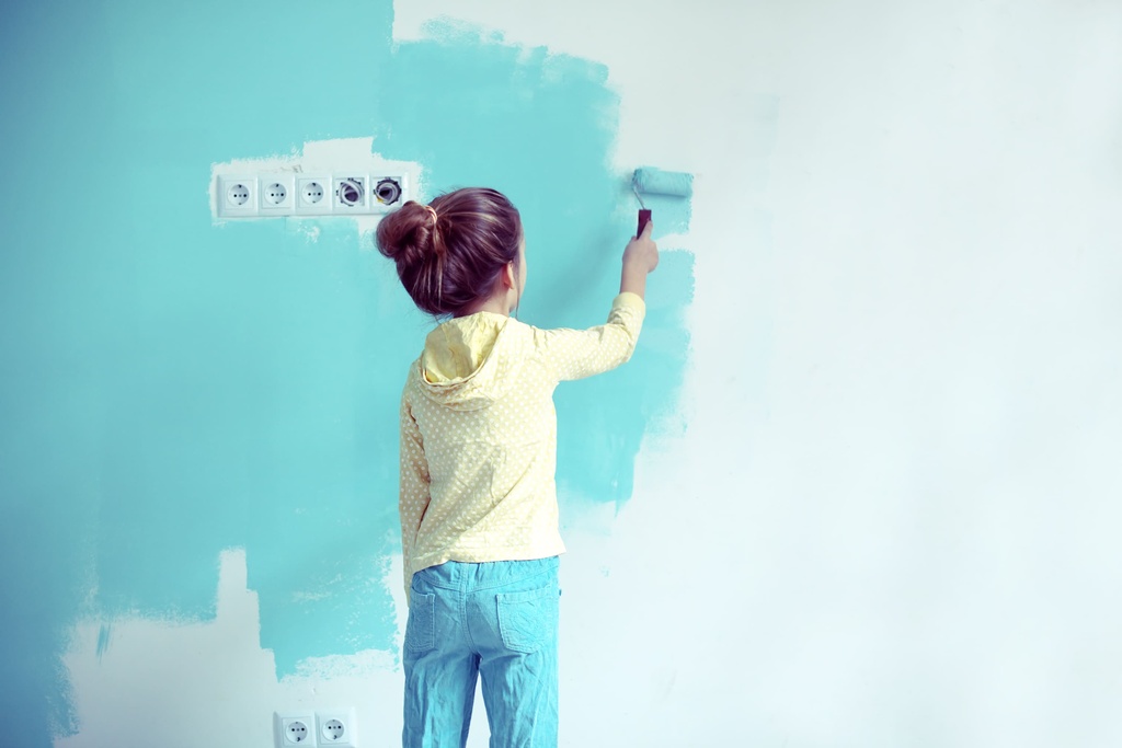 criança pintando parede com tinta em tom azul