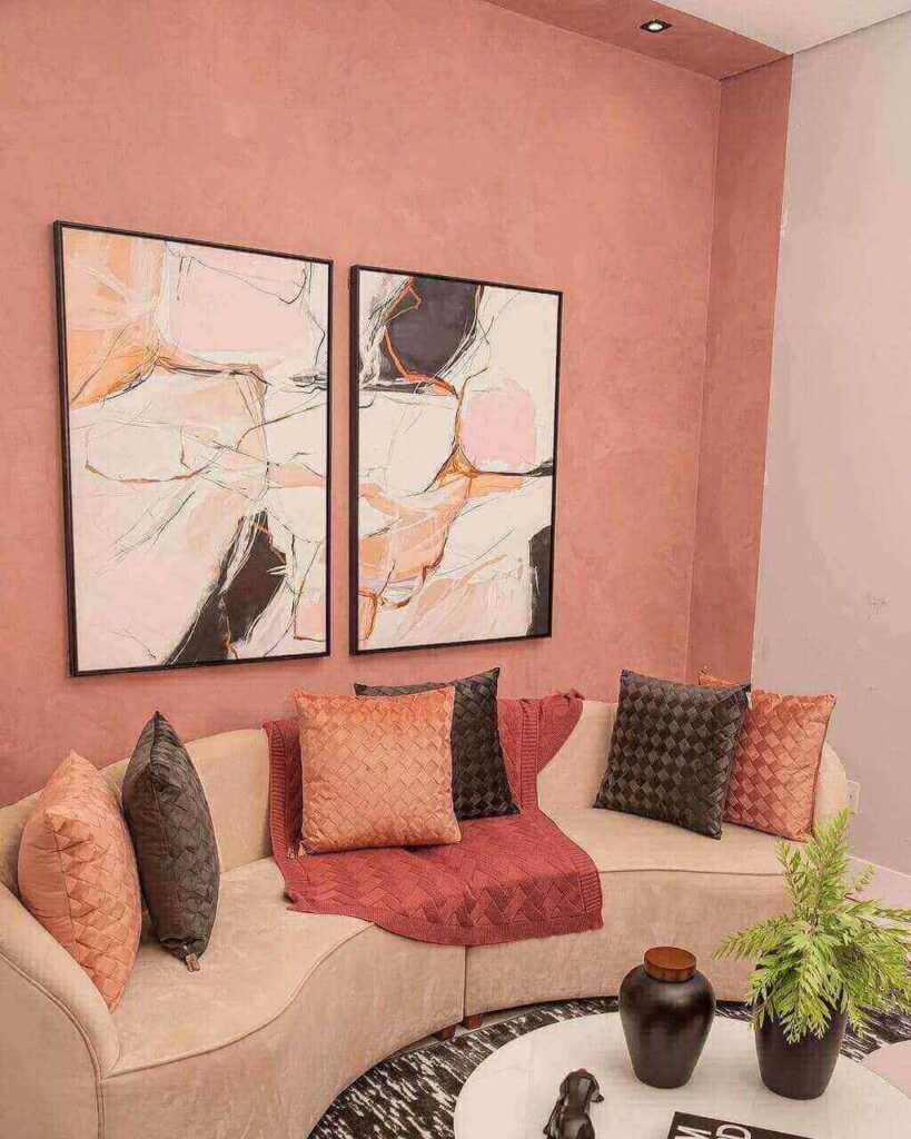 sala com parede rosa, sofá, quadros e almofadas coloridas