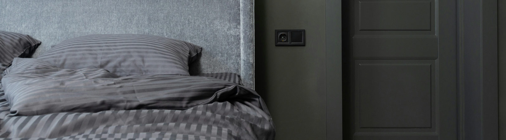 Parede, porta e roupa de cama na tonalidade cinza.